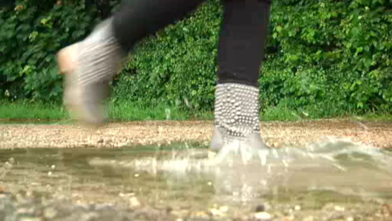 Frau rennt bei Regen durch eine Pfütze