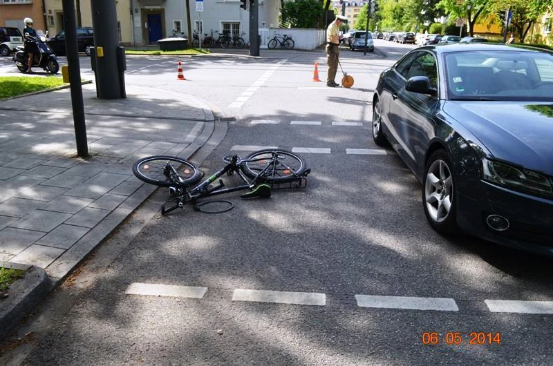 Symbolfoto eines Fahrradunfalls mit einem Auto, Polizist im Hintergrund — © Symbolfoto