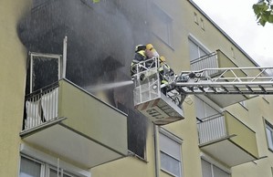 Feuerwehrmänner löschen einen Brand von der Hebebühne aus, © Ein 34-Jähriger setzte vermutlich seine Wohnung aus Verzweiflung in Brand Foto: Feuerwehr München