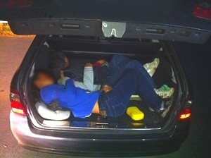 Flüchtlinge zusammengekauert in einem Schleuser-Kofferraum