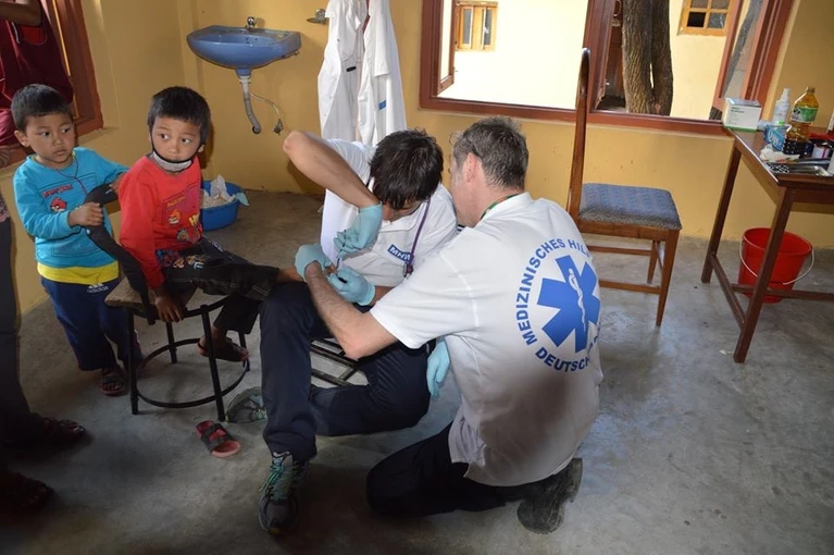 Ein Helfer kümmert sich um vom Erdbeben verletzte Kinder in Nepal — © Die Helfer in Nepal haben vor Ort alle Hände voll zu tun Foto: MHW