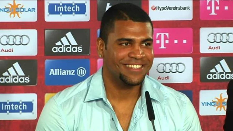 Breno sitzt bei einer Pressekonferenz und lächelt — © Breno kann wieder lächeln Foto: Archiv