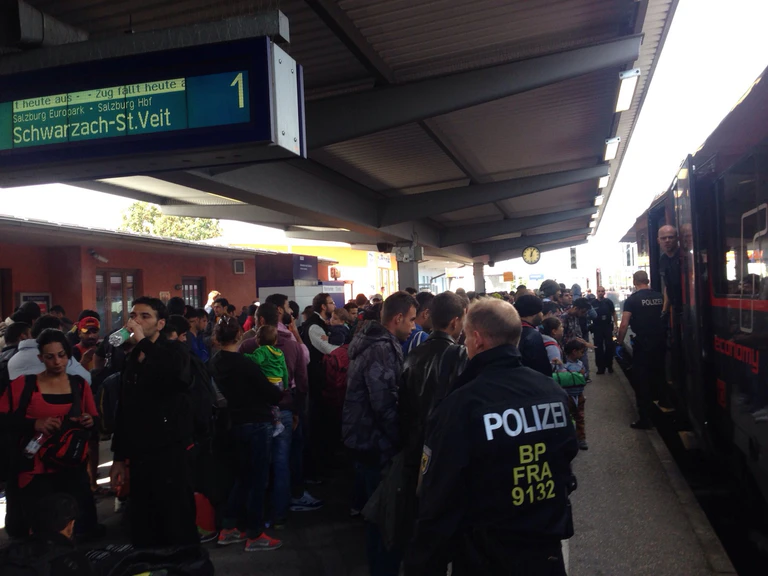 Am Bahnhof in Freilassing stehen eben angekommene Flüchtlinge