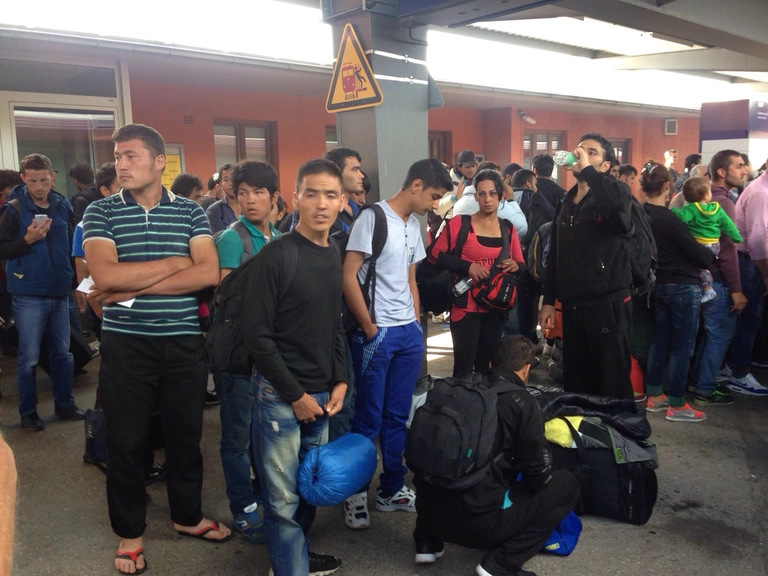 Am Bahnhof in Freilassing stehen eben angekommene Flüchtlinge — © Bayern will eine Obergrenze für Flüchtlinge