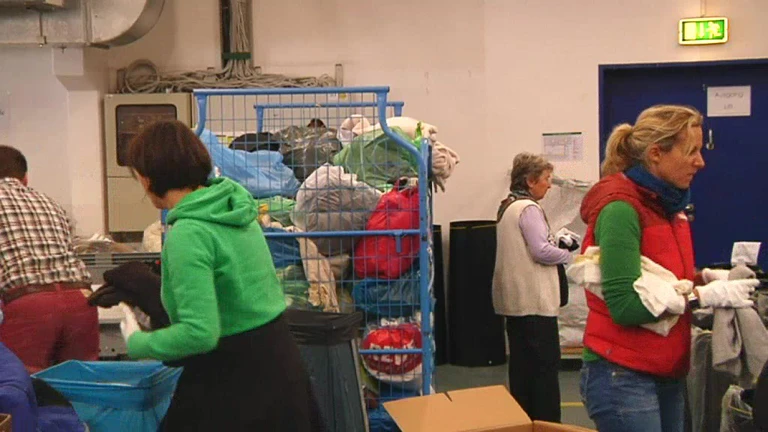 Diakonia Helfer sortieren in Raum die gespendeten klamotten für flüchtlinge — © Diakonia