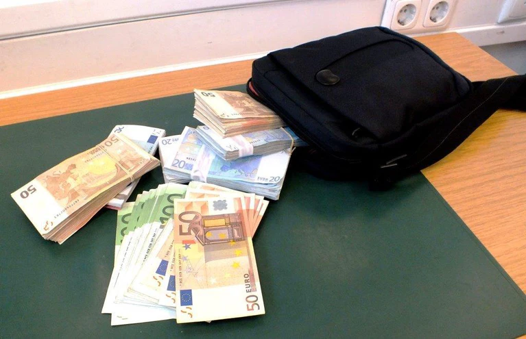 Geldbündel liegen auf dem Tisch neben einer Tasche — © Foto: Bundespolizei München