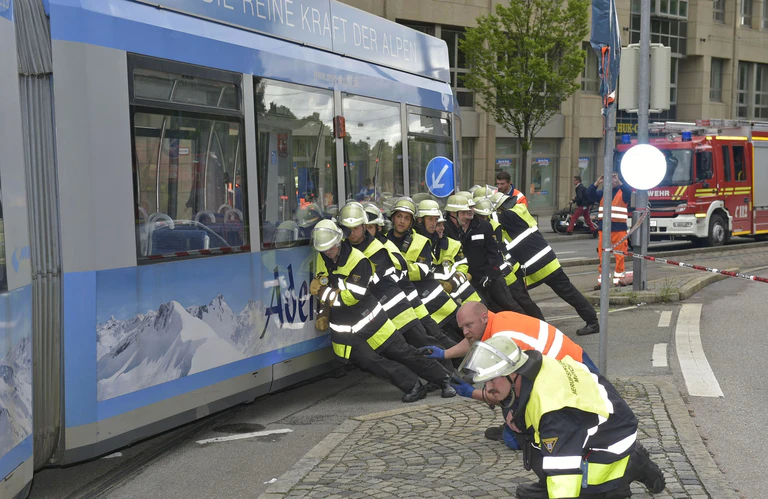 Feuerwehrmänner schieben seitlich Trambahn wieder in die Gleise — © Feuerwehr München