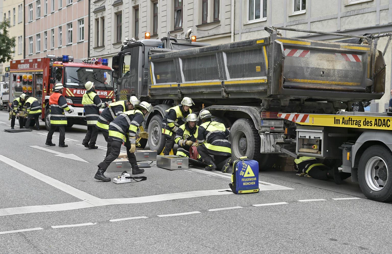 Einsatzkräfte der Feuerwehr, retten Frau unter Laster — © Feuerwehr München