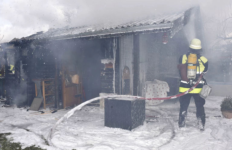 Ein Feuerwehrmann löscht das Gartenhaus im Olympiapark — © Rechte: Kreisverwaltungsreferat Branddirektionsstelle