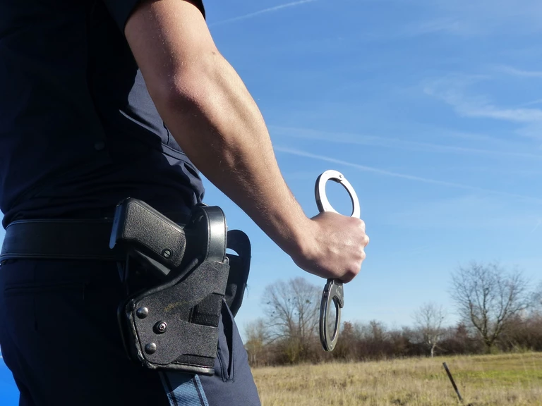 Polizist mit Handschellen — © Symbolfoto