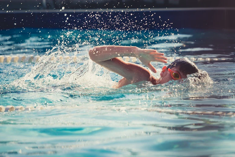 Ein Kind, das im Becken schwimmt und das Schwimmen übt.