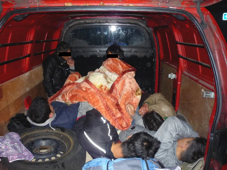 — © Flüchtlinge zusammengekauert in einem Schleuser-Kofferraum