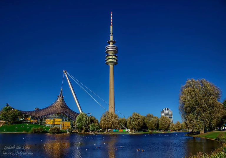 Der Olympiaturm und der Olympiasee München — © <a href="https://www.facebook.com/pages/Janusz-Lubojansky-Behind-the-Lens/1500974093511137?fref=ts/" target="_blank">Der Olympiaturm und der Olympiasee - Bild: Janusz Lubojansky - Behind the Lens</a>