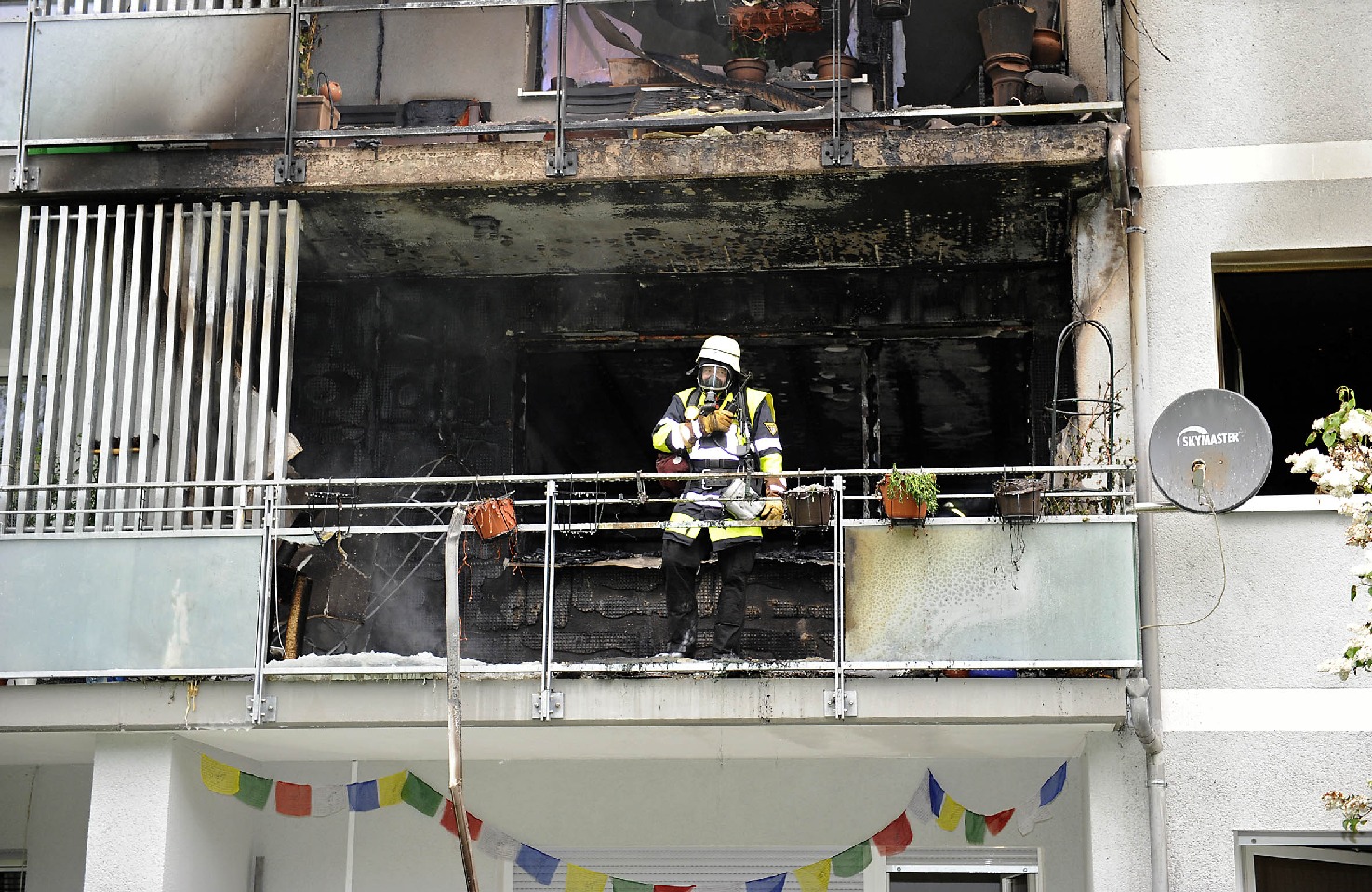 Ein Münchner Feuerwehrmann steht erschöpft auf dem Balkon des verbrannten Hauses, Erschöpft nach dem Brand: Ein Münchner Feuerwehrmann Foto: Berufsfeuerwehr München