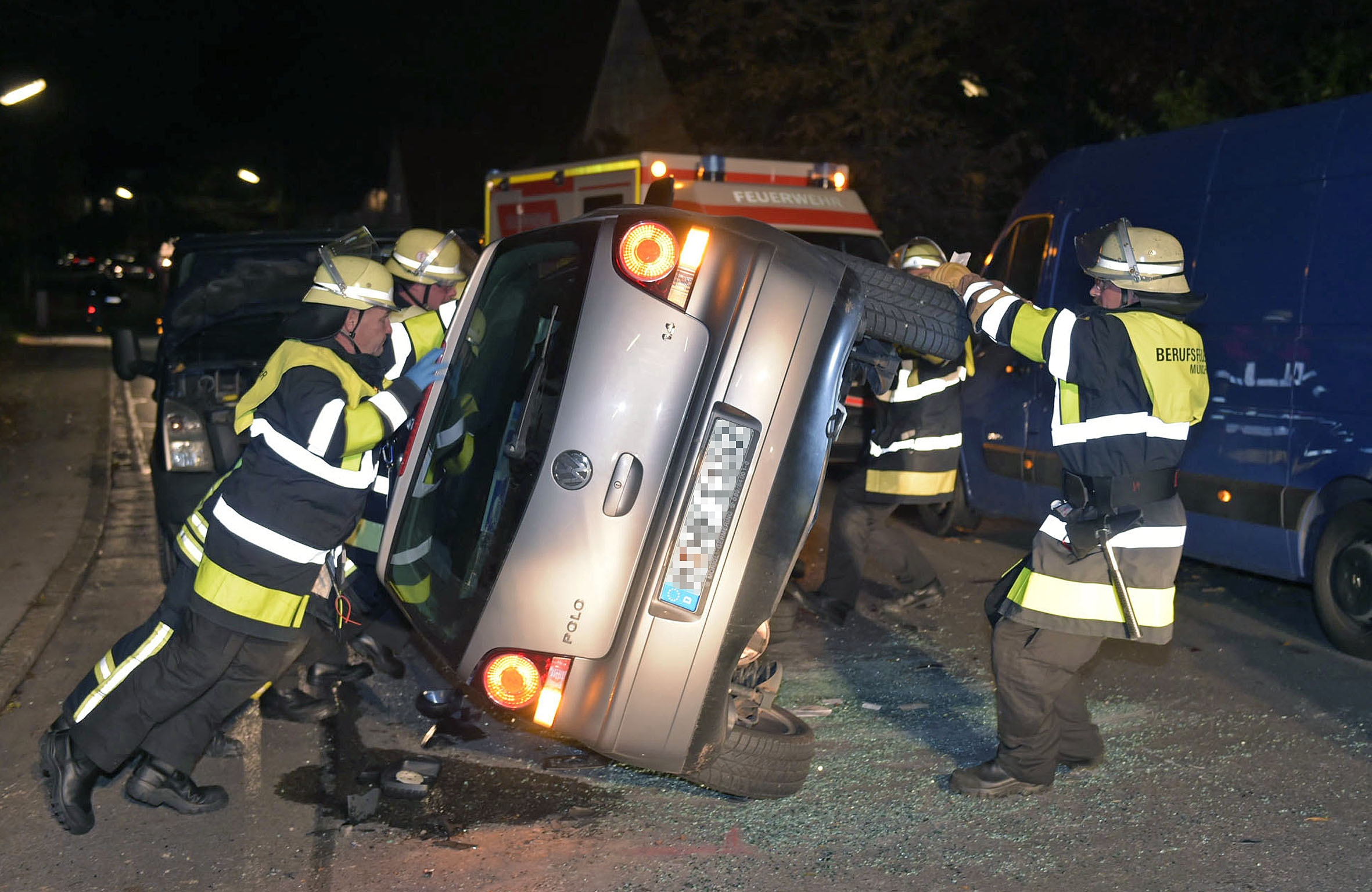 Helfer der Feuerwehr kippen den Unfallwagen wieder auf die Räder, Feuerwehr München